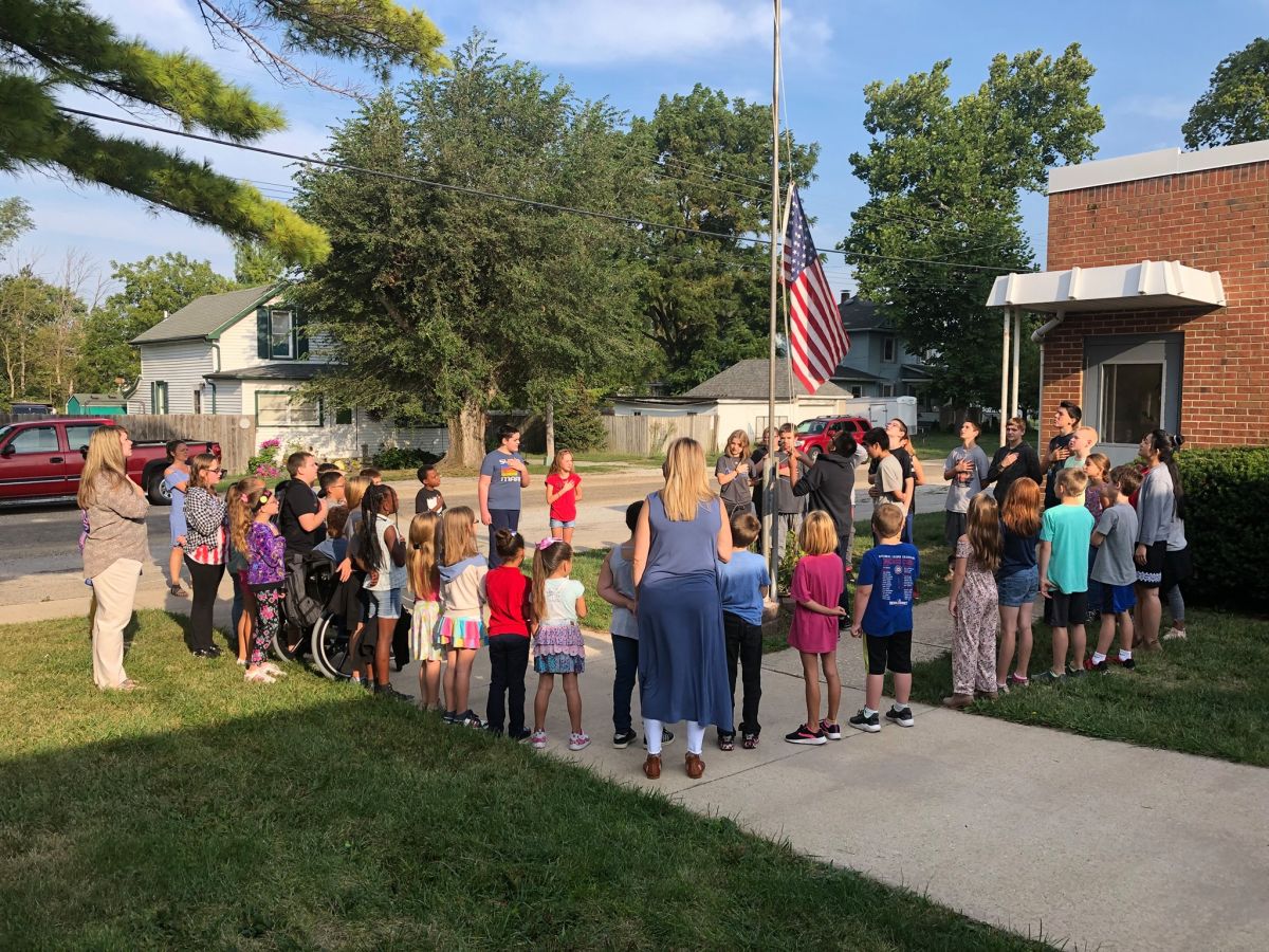 Students and staff encircle the flag pole to recite the Pledge of Allegiance.